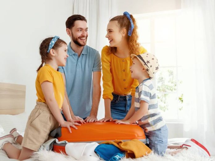 Laughing,Kids,And,Parents,Gathering,On,Bed,Closing,Suitcase,Together